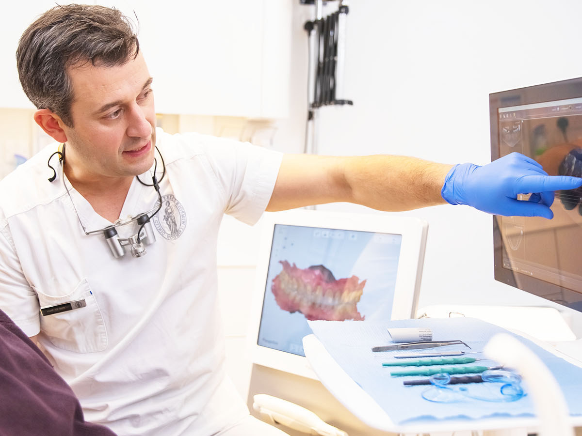 A dentist explaining a scan of the jaw on screen